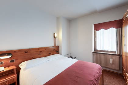 Pokój hotelowy z łóżkiem, szafką nocną i oknem.