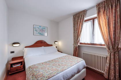 Pokój hotelowy z łóżkiem i oknem zasłoniętym zasłonami.