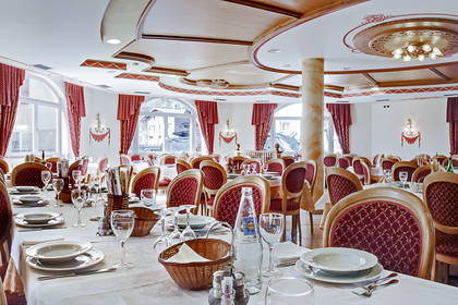 Sala restauracyjna z nakrytymi stołami i krzesłami czeka na gości.