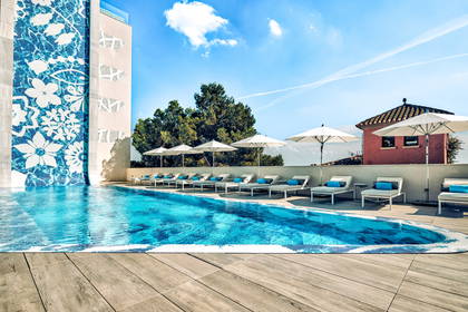 Basen hotelowy z leżakami i parasolami.
