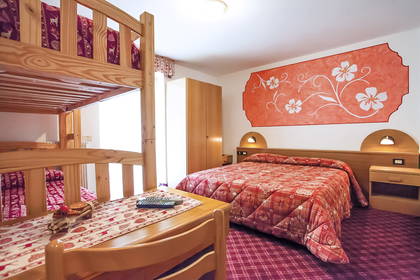 Pokój hotelowy z łóżkiem piętrowym, biurkiem i łóżkiem podwójnym.