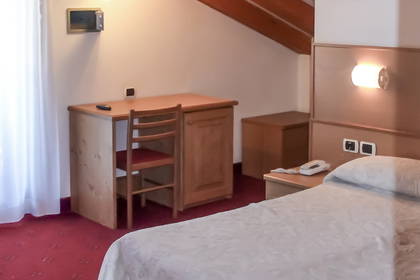 Pokój hotelowy z łóżkiem, biurkiem i drewnianym sufitem.