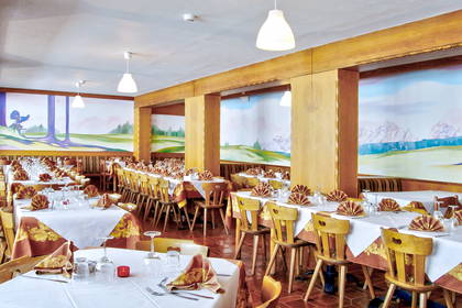 Restauracja z tradycyjnie nakrytymi stołami i krzesłami.