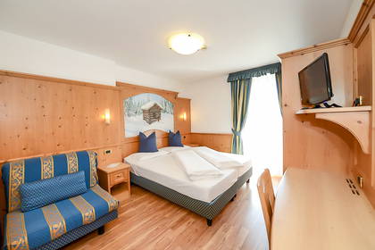 Pokój hotelowy z łóżkiem, sofą, biurkiem i telewizorem.