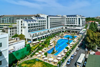 Luksusowy hotel z basenem, parasolami i zielenią, widok z góry.