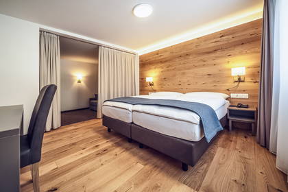 Pokój hotelowy z łóżkiem, biurkiem i ścianą wyłożoną drewnem.