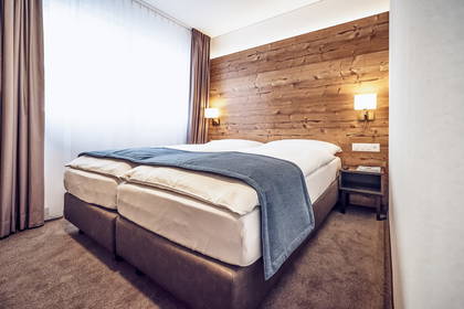 Pokój hotelowy z dwoma łóżkami, drewnianą ścianą i lampkami nocnymi.