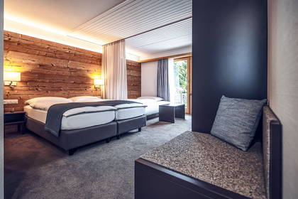 Pokój hotelowy z łóżkiem, drewnianą ścianą i balkonem.