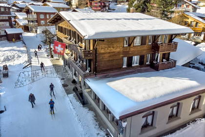 Zimowy krajobraz w Alpach z hotelem i narciarzami.