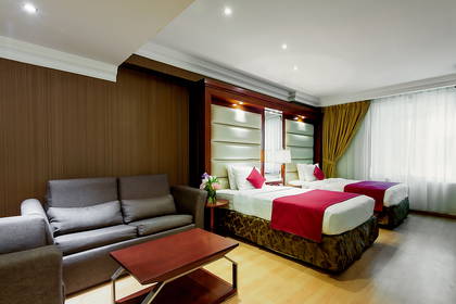 Pokój hotelowy z dwoma łóżkami i sofą.