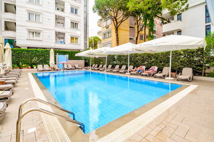 Basen z leżakami i parasolami przy hotelu.
