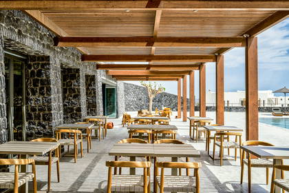 Restauracja na zewnątrz z drewnianą pergolą i kamiennymi ścianami.