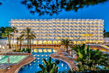 Hotel z basenami i palmami o zmierzchu.
