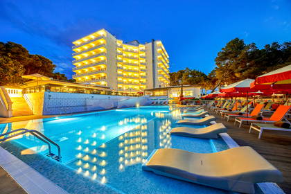 Hotel z basenem i leżakami nocą.