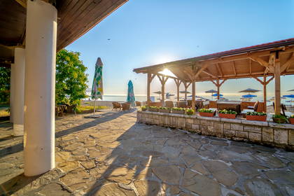 Patio z widokiem na plażę i morze. W tle widoczne parasole.