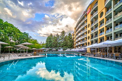 Basen w hotelu z mostkiem. W tle budynek.