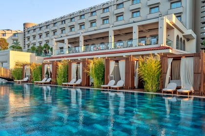 Basen hotelowy z leżakami i pawilonami.