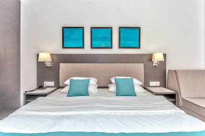 Pokój hotelowy z łóżkiem, stolikami nocnymi i obrazami na ścianach.