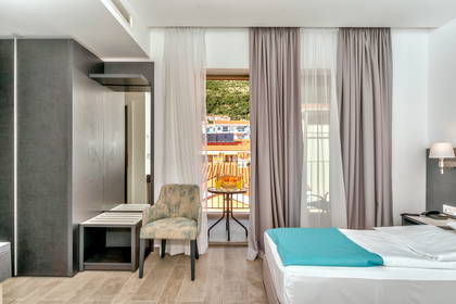 Pokój hotelowy z łóżkiem, krzesłem i balkonem. Widok z balkonu.
