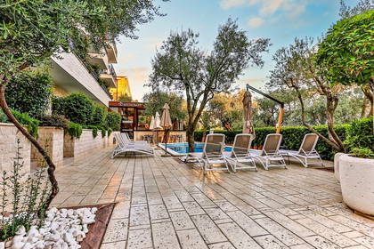 Patio z basenem, leżakami i roślinami.