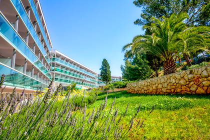 Hotel z balkonami w otoczeniu palm w słoneczny dzień.
