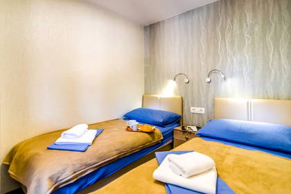 Pokój z dwoma pojedynczymi łóżkami, przykrytymi niebieską pościelą i brązowymi kocami.