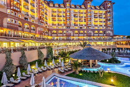 Hotel z basenami oświetlonymi nocą. Przy basenach stoją parasole.