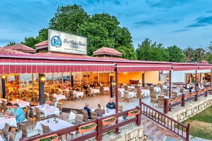 Restauracja z ogródkiem i gośćmi przy stolikach.