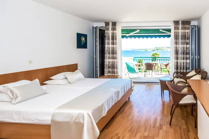 Pokój hotelowy z balkonem i widokiem na morze.