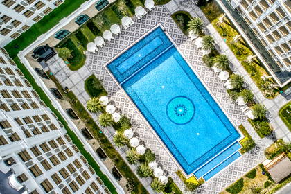Basen z dekoracyjnym wzorem otoczony hotelami i zielenią, widok z góry.