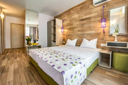 Pokój hotelowy z łóżkiem, szafkami nocnymi i ścianą wyłożoną drewnem.