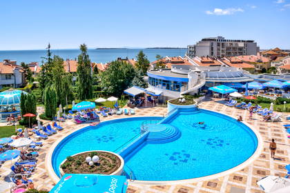 Okrągły basen hotelowy z leżakami, widok z góry. W tle morze.