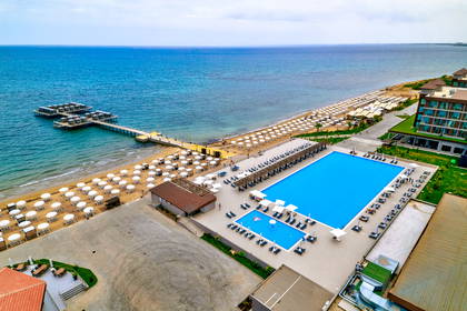 Widok z lotu ptaka na hotel z basenem, plażą i pomostem.