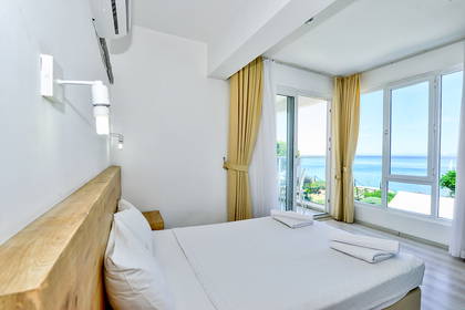 Jasny pokój hotelowy z łóżkiem i widokiem na morze.