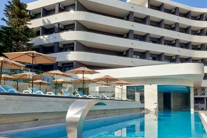 Hotel z basenem i strefą relaksu z leżakami i parasolami.