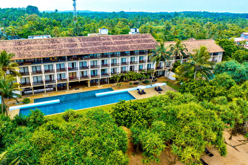 Hotel z basenem wśród tropikalnej roślinności.