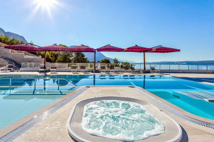 Basen z jacuzzi i leżakami do opalania.