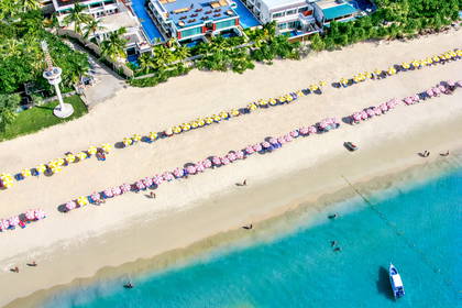 Plaża z parasolami i budynkami widziana z góry.