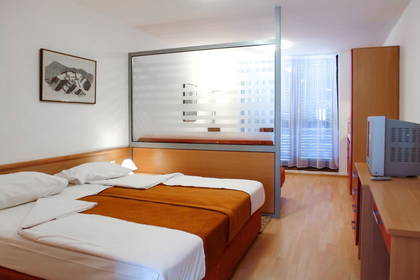 Pokój hotelowy z łóżkiem, szafką i telewizorem.