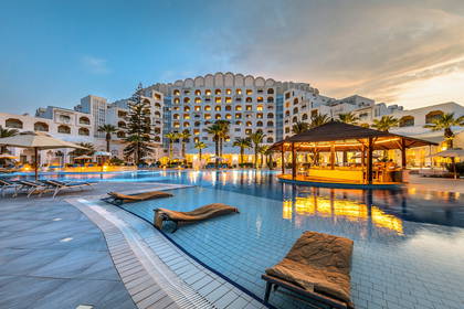 Hotel z basenem i barem wodnym o zmierzchu.