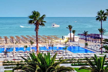 Hotelowy basen z widokiem na plażę i morze. W oddali widoczne łodzie.