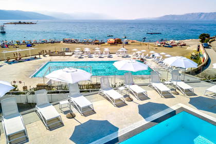 Hotelowy basen i plaża z leżakami oraz parasolami.