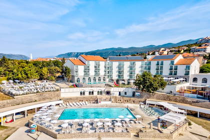 Hotel z basenami i leżakami w słoneczny dzień.