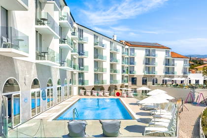 Hotel z basenem i leżakami w słoneczny, upalny dzień.