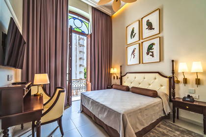 Pokój hotelowy z balkonem, biurkiem i łóżkiem.