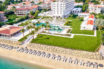 Widok z lotu ptaka na hotel z basenem, plażą i osobą kąpiącą się w morzu.