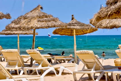 Plaża z leżakami i parasolami. W tle widok na morze.