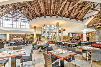 Przestronna restauracja z wysokim sufitem i nakrytymi stołami.