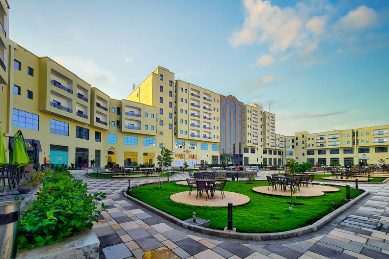 Hotel z patio, krzesłami i trawnikami.