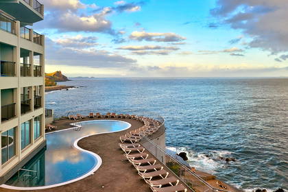 Hotelowy basen z leżakami nad oceanem.